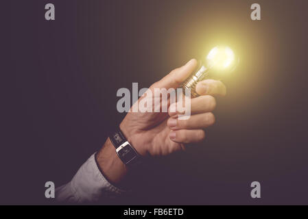 Businessman holding light bulb, concept of new ideas, business innovation and creativity, retro toned image, selective focus. Stock Photo