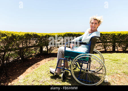 happy disabled middle aged woman sitting outdoors Stock Photo