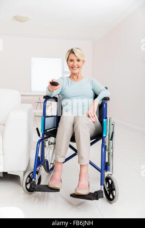 cheerful disabled senior woman watching television in living room Stock Photo