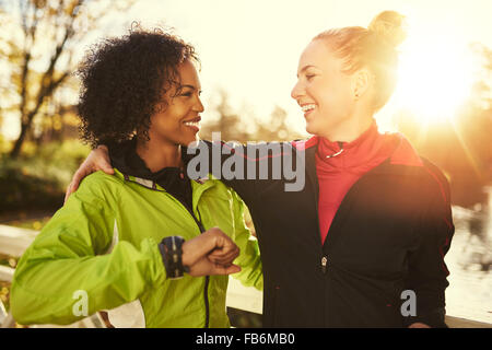 Two smiling sportswomen hugging while standing outdoors Stock Photo