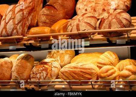 Various kinds of fresh baked artisan bread on the shelves in the bakeshop. Stock Photo