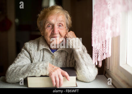 An old woman sits with a book. Stock Photo