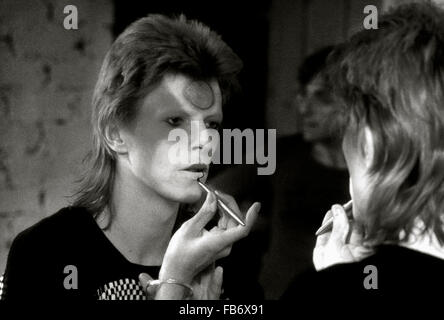 Lewisham, London, England, UK. 22 May 1973. David Bowie applying Ziggy Stardust makeup  in dressing room backstage. His guitarist Mick Ronson is behind him and can be seen reflected in the mirror. Roger Bamber/Alamy Live News Stock Photo