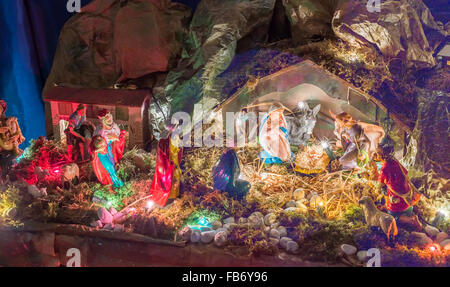 Statues in a Christmas Nativity scene, the Blessed Virgin Mary and Saint Joseph watch over the Holy Child Jesus in a manger in the straw as the ox and the donkey are warming while the three wise men bring gifts of gold, frankincense and myrrh Stock Photo