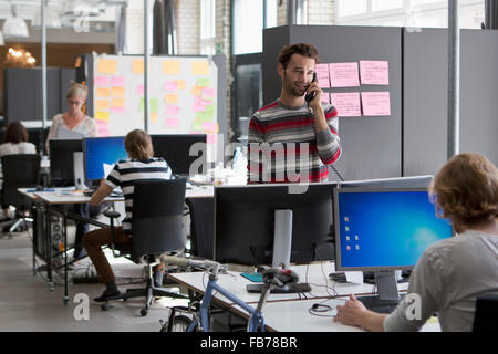 Colleagues working in office, man talking on landline phone Stock Photo