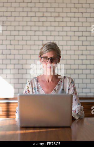 Woman sitting at table using laptop Stock Photo