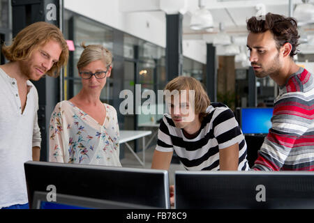 Office colleagues looking at computer in office Stock Photo