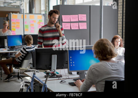 Colleagues working in office, man talking on landline phone Stock Photo