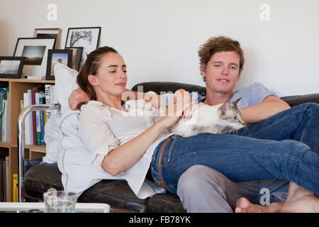 Young couple lying on sofa with cat Stock Photo