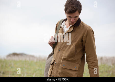 Man wearing brown jacket carrying backpack, close-up Stock Photo