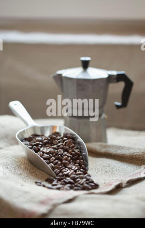 Scoop full of coffee beans with coffee maker on sack Stock Photo