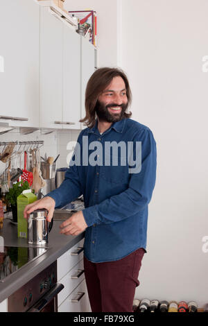 Smiling man looking away while standing at kitchen counter Stock Photo