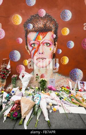 London, Britain. 11th Jan, 2016. Fans pay their respects with flowers and messages at a David Bowie mural in Brixton, South London, Britain, on Jan. 11, 2016. David Bowie, the iconic British singer-songwriter died on Sunday, just two days after his 69th birthday, his family announced Monday in a brief statement. © Ray Tang/Xinhua/Alamy Live News