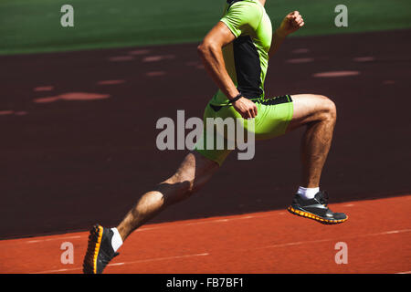 Low section of sporty young man running on race track Stock Photo
