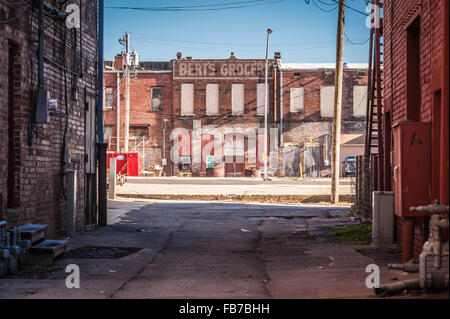 Old, painted-brick signage on boarded-up building seen through alleyway in downtown Muskogee, Oklahoma, USA. Stock Photo