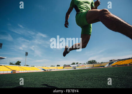Low section of young male athlete running on field in stadium Stock Photo