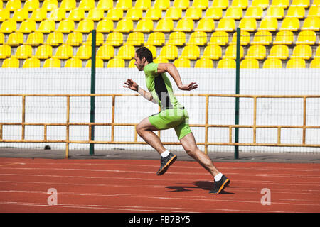 Full length side view of sporty young man running on race track in stadium Stock Photo