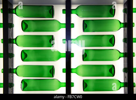 Decorative pattern of green glass bottles arranged in rows facing in alternating directions with back lighting Stock Photo