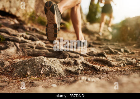 Cross country running. Closeup of male feet run through rocky terrain. Focus on shoes. Stock Photo