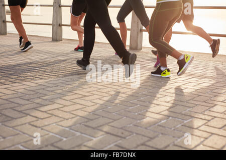 Legs of runners training together on seaside promenade. People running on the street by the sea. Stock Photo