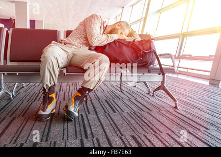Canceled flight Man sleeping on his travel luggage Stock Photo