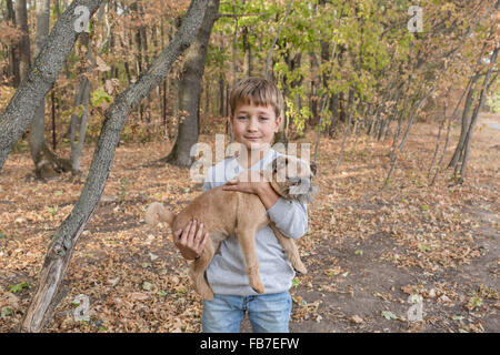 Portrait of cute boy carrying dog in forest Stock Photo