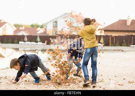 Children playing with dry leaves on footpath Stock Photo