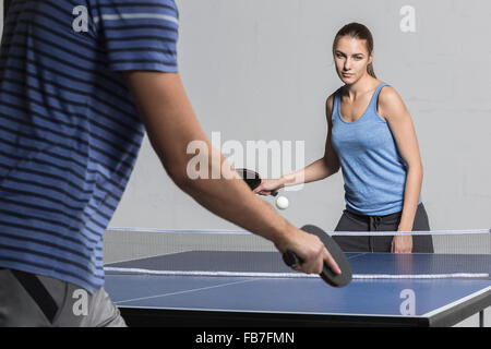 Confident young woman playing table tennis with man Stock Photo