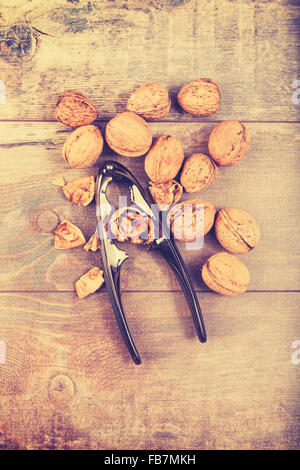 Vintage stylized walnuts and nutcracker on wooden background, space for text. Stock Photo