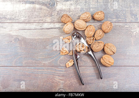 Walnuts and nutcracker on wooden background, space for text. Stock Photo