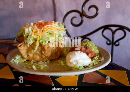 Southwestern, Mexican salad presentation in fried taco nest with threescoops of sour cream, tomato salsa, and guacamole Stock Photo