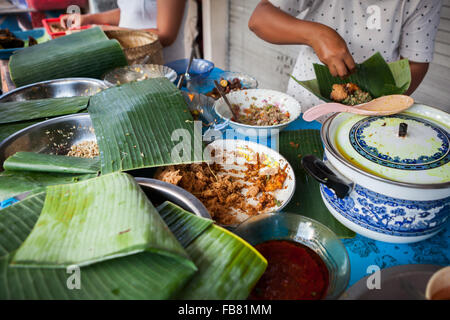 A woman serving customers at a street-side food vendor offering traditionally cooked food in Klungkung, Bali, Indonesia. Stock Photo