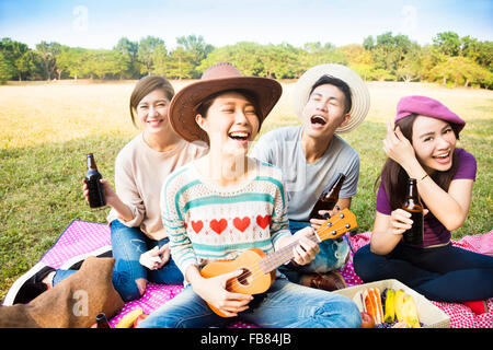 happy young friends enjoying picnic and playing ukulele Stock Photo