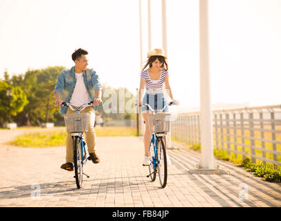 happy young couple riding on bicycle in city park Stock Photo