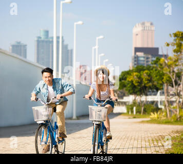 happy young couple riding on bicycle in city park Stock Photo