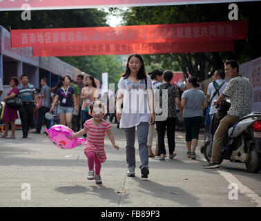A mixed-race toddler runs ahead of her Chinese mother at a trade fair in a city in China.