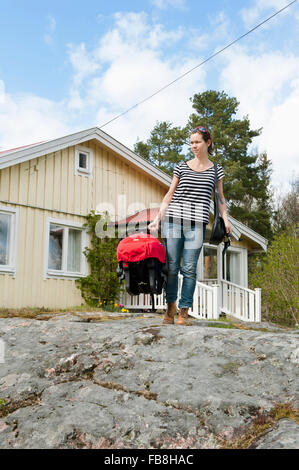 Sweden, Ostergotland, Vikbolandet, Mid-adult woman carrying moses basket with baby girl (6-11 months) Stock Photo