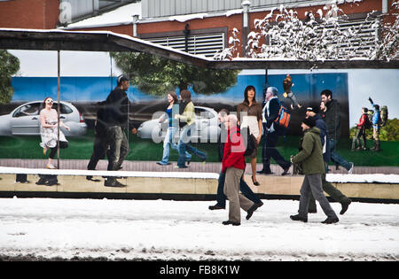 People in winter walking by an advertising hoarding, Sheffield, Yorkshire. Stock Photo
