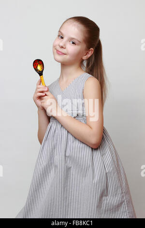 Beautiful european little girl holding Art spoon in russian Hohloma style Stock Photo