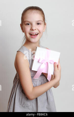Lovely smiley little girl holding white gift box with pink ribbon Stock Photo