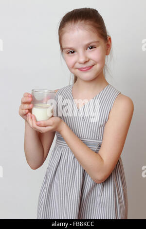 European smiley little girl holding white cow milk in glass Stock Photo