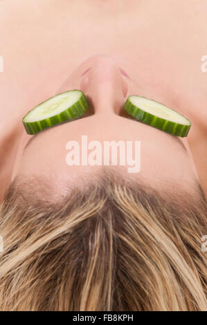 Woman with slices of cumbers covering her eyes Stock Photo