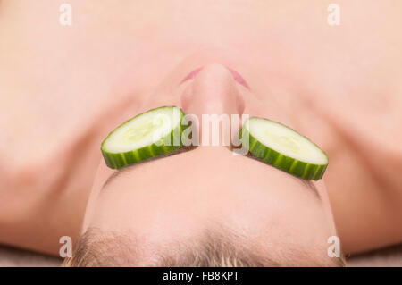 Woman with slices of cumbers covering her eyes Stock Photo
