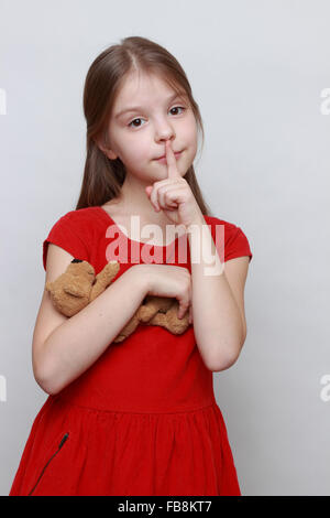 Beautiful little girl in red fashion dress holding lovely toy teddy bear Stock Photo