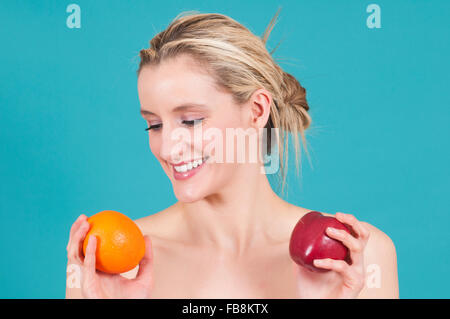 WOman comparing apples to oranges Stock Photo