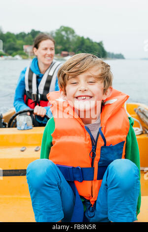Sweden, Uppland, Runmaro, Barrskar, Portrait of boy (6-7) on motorboat, mother in background