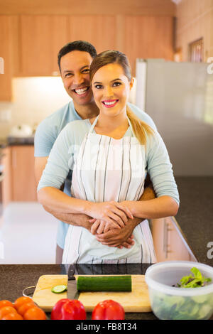 happy couple embracing in kitchen while preparing dinner Stock Photo