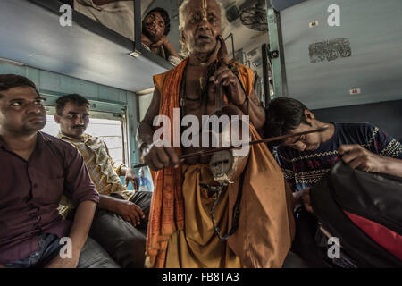 Traveling musician playing for passengers on an Indian train. Stock Photo