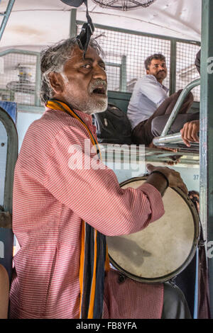 Traveling musician playing for passengers on an Indian train. Stock Photo