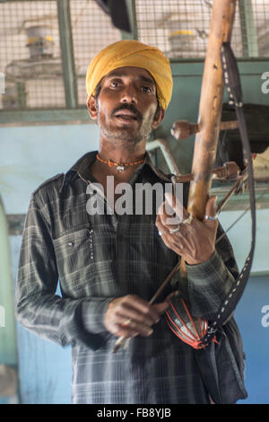 Traveling musician playing for passengers on an Indian train. Stock Photo